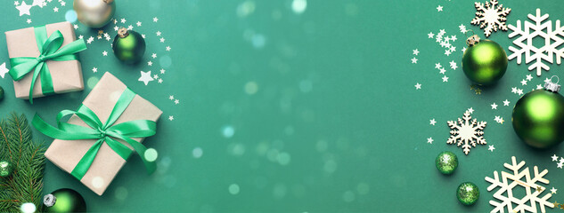 Christmas balls, gift boxes and snowflakes on green background, top view. Greeting card or poster