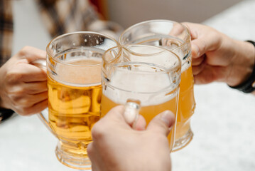 clinking glasses of beer, company of friends in bar, three men and three glasses of beer
