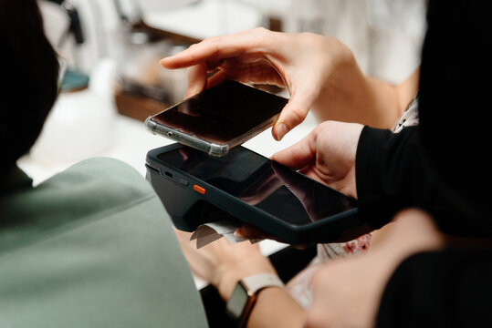 waitress holding in hands electronic cash register for contactless payment with paper receipt in cafe or restaurant, client attaching smartphone and paying with smartphone, smart terminal concept