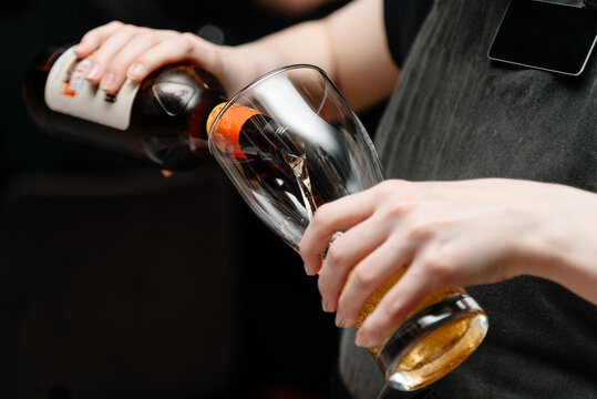 bartender pours light beer into large beer mug for customer at bar, close-up view of hand holding mug and bottle - Powered by Adobe