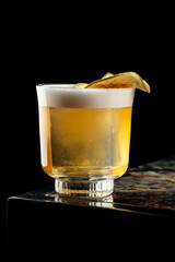 Close-up view of the middle of a Maple Whiskey Sour cocktail in a rocks glass, highlighting the amber liquid and citrus twist garnish.