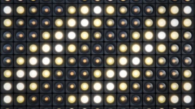 Flashing bright retro studio spot lights or bulbs grid in dark environment making diagonal lines, repeating animation. 