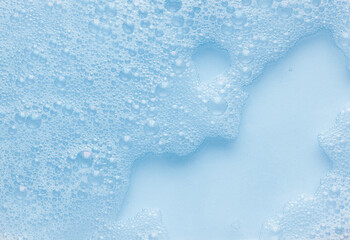 Abstract blue background with delicate soap foam bubbles in light tinted water, creating soft texture and airy pattern useful for clean design, spa themes, hygiene concepts and minimal aesthetics