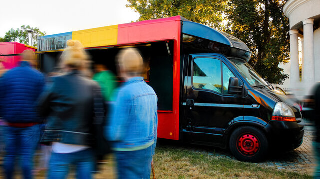 Street Food Truck Car with Belgian-Style Colors with People Lining Up Around it on a Sunny Summer Day. Good for Food or Business Presentation.