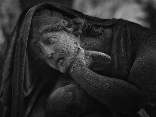 Weathered stone mourning figure at Goat Gate Cemetery in Bratislava, photographed in dramatic black and white.