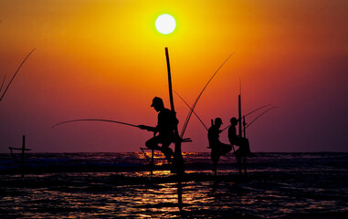 traditional stilt fishermen of sri Lanka fishing at sunset