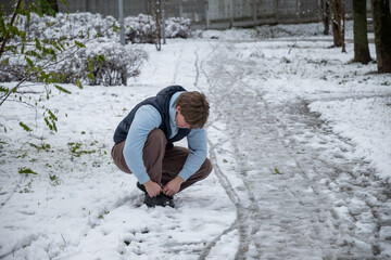 Fototapeta premium Man tying shoes in snowy winter park. Outdoor Lifestyle