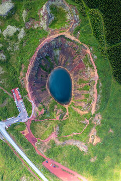 Aerial view of the Kerio Crater's vibrant blue lake surrounded by steep red volcanic slopes and lush green vegetation, Klausturholar, Gr&iacute;msnes- og Grafningshreppur, Iceland.