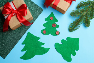 Christmas gifts, handicraft materials and fir branch on light blue background, flat lay. Child handmade craft