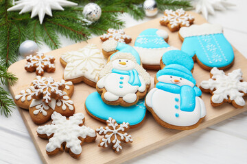 Tasty gingerbread cookies and Christmas decor on white wooden table, closeup