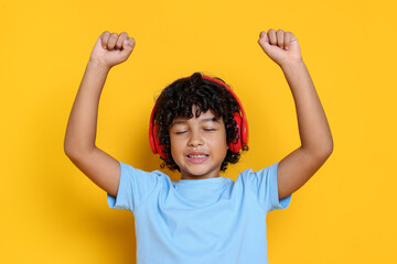 Portrait of little boy with headphones on yellow background