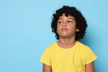 Portrait of sad little boy on light blue background, space for text