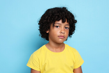 Portrait of sad little boy on light blue background