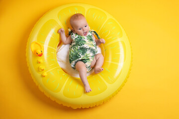 Cute little baby with toy ducks on inflatable ring against orange background, top view