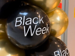 Elegant black, glossy gold balloons feature Black Week text, signifying major promotional sales, discount offers, and exciting holiday shopping events