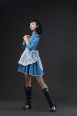 Naklejka premium Gothic-style woman in blue Victorian dress with apron, Alice in Wonderland theme