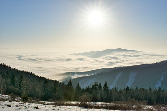 Aerial view of the sun shining over a sea of clouds obscuring the mountain range, with a forest in the foreground, Spisska nova Ves, Kosicky kraj, Slovakia.