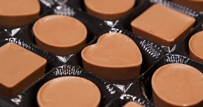 Valentines Day Gift. Candies are round, square and heart-shaped. Chocolate candies in a packaging. Delicious chocolate candy with of different forms, including heart-shaped ones