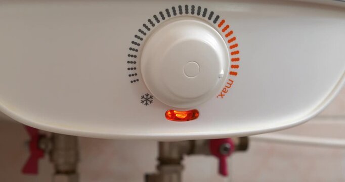 Boiler to heat water. The red indicator is on. Regulator of temperature of heating water in boiler. Boiler heats water from cold water supply system