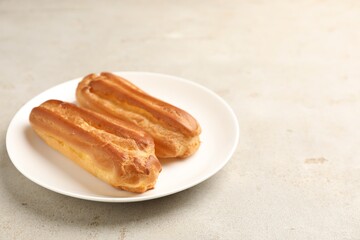 Fresh tasty eclairs on light table, closeup. Space for text