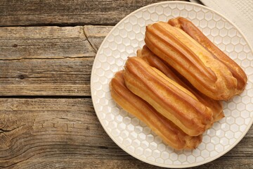 Fresh tasty eclairs on wooden table, top view. Space for text