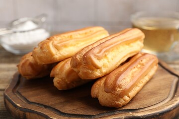 Fresh tasty eclairs on wooden board, closeup