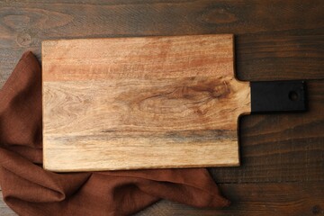One cutting board and napkin on wooden table, top view. Space for text