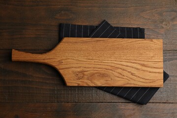One cutting board and napkin on wooden table, top view. Space for text