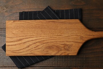One cutting board and napkin on wooden table, top view. Space for text