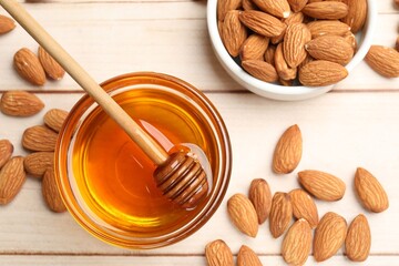Honey with almond nuts and dipper on wooden table, flat lay