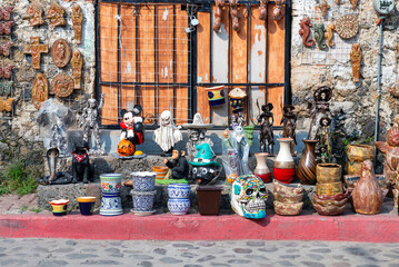 Outdoor market display of colorful souvenirs, Halloween decorations, and ceramic pots.