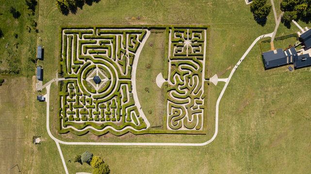 Aerial view of a symmetrical maze with intricate patterns and lush green hedges, a geometric puzzle contrasting with the surrounding open fields, El Hoyo, Chubut Province, Argentina.