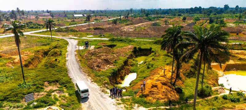 Aerial view of a landscape where scars of excavation meet the vibrant green of nature, with a group of people gathered near a bus, Ogale, Eleme, Rivers State, Nigeria