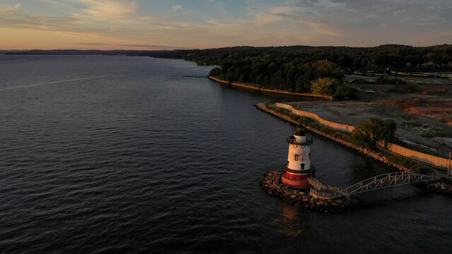 Aerial view of the Sleepy Hollow Lighthouse stands sentinel as the Hudson River reflects the golden hues of the setting sun, Tarrytown, New York, United States.