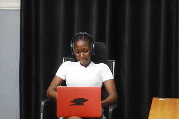 Young African lady using laptop. Woman working on computer using phone