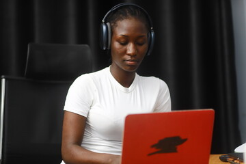 Young African lady using laptop. Woman working on computer using phone