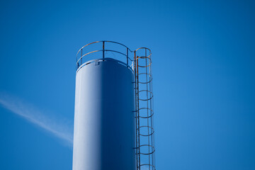 Tall industrial blue storage tank with metal ladder.