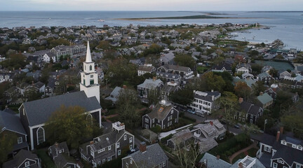 Aerial view of the First Congregational Church steeple rising above the quaint rooftops of a historic town nestled by the calm ocean, Nantucket, Massachusetts, United States.