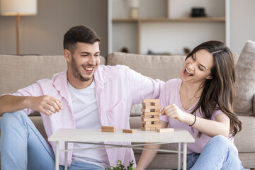Couple enjoys a fun game of Jenga at home on a cozy afternoon, sharing laughter and friendly competition