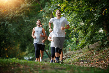 Group of friends running together on a sunny day in a park during the late afternoon