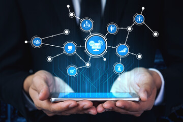 A business professional hands are shown holding a smartphone displaying a vibrant digital network of interconnected icons, symbolizing modern technology and business connectivity. Tessel