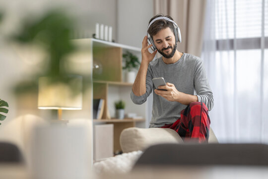 Relaxing at home while listening to music with headphones and a smartphone in cozy attire
