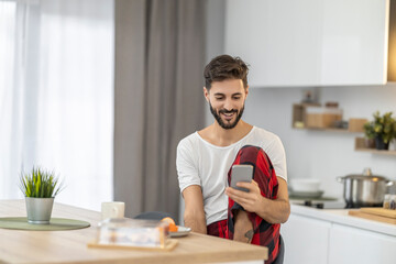 Man enjoying morning routine while using smartphone in modern kitchen with natural light