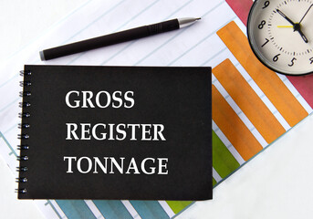 GROSS REGISTER TONNAGE - words on a black notebook with a chart and alarm clock in the background