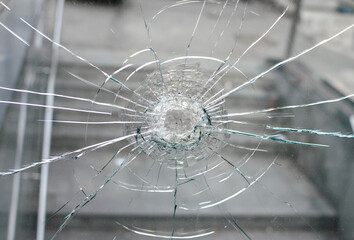 Radial impact–damaged cracked glass surface with shattered center