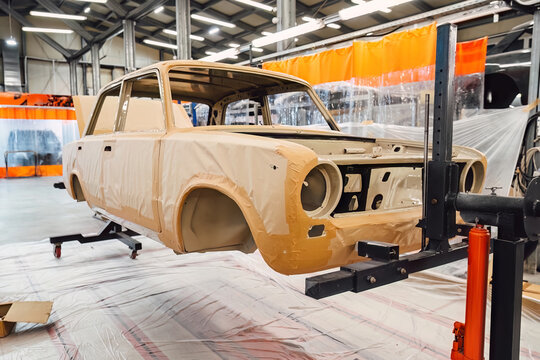 Specialist spraying anti rust sealant into the hidden chassis cavities. Protection against corrosion and internal body element sealing in a professional auto service shop