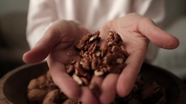 Closeup video of cracking walnuts using special tool. Nuts in a vintage wooden bowl. Healthy snack rich in fiber, fat and nutrients. Removing shell from walnuts. 