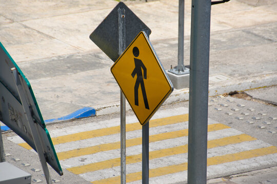 A yellow pedestrian crossing sign on a crossroad