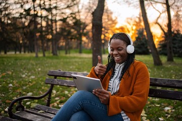 Young adult woman video calling family and friends in park