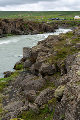 Icelandic landscape with a river and rocks in the foreground.